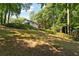 A sloped backyard showcases trees and the rear of the home with deck at 1590 Sunnybrook Farm Rd, Atlanta, GA 30350