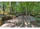 Backyard with mature trees and stone patio area at 1590 Sunnybrook Farm Rd, Atlanta, GA 30350