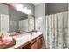 Well-lit bathroom features an ample vanity, a large mirror, and a shower with floral curtain at 918 Harvest Brook Dr, Lawrenceville, GA 30043