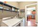 The laundry room has a washer, dryer, blue shelves, and a view into the kitchen with wood floors at 918 Harvest Brook Dr, Lawrenceville, GA 30043