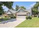 Exterior view of a well-maintained home featuring a two-car garage, manicured lawn, and charming architectural details at 1875 Conners Ct, Lawrenceville, GA 30044