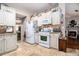Clean kitchen with white appliances and cabinets, tile floors, and a view into the living space at 1875 Conners Ct, Lawrenceville, GA 30044