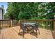 Wooden back deck featuring an outdoor dining set and overlooking lush greenery at 507 Mirramont Pl, Woodstock, GA 30189