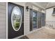 Close-up of a home's front porch with an oval glass front door and paneled windows with dark shutters at 507 Mirramont Pl, Woodstock, GA 30189