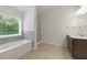 Primary bathroom with shower, tub, vanity, tile floor and a large window at 2445 Whitehead Place Dr, Suwanee, GA 30024