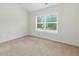 Cozy bedroom features neutral carpet, white walls, and a view of the home across the street at 2445 Whitehead Place Dr, Suwanee, GA 30024