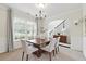 Elegant dining room with large window, chandelier, wainscoting, and neutral tones; staircase visible at 2445 Whitehead Place Dr, Suwanee, GA 30024