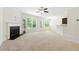 Open-concept living room featuring a fireplace, neutral carpeting, and access to an outdoor balcony at 2445 Whitehead Place Dr, Suwanee, GA 30024