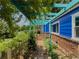Cozy side entrance with a turquoise pergola adorned with greenery leading to the brick entryway at 5130 Dearing St, Covington, GA 30014