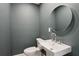 Modern powder room features gray walls, white sink, round mirror, and sleek fixtures for a minimalist design at 600 Applewood Nw Ln, Marietta, GA 30064
