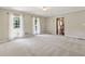 Large living room featuring neutral carpet and walls, natural light, and a view of the staircase in the distance at 3835 Thornhill Sw Dr, Lilburn, GA 30047