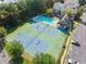 Overhead view of tennis courts next to pool, all surrounded by trees, parked cars and townhomes at 2345 Gallard St, Lawrenceville, GA 30043