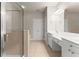 Bright bathroom featuring a glass shower, double vanity with white cabinets and neutral tile flooring at 2345 Gallard St, Lawrenceville, GA 30043