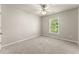 A carpeted bedroom with neutral walls, ceiling fan, and a window with trees outside at 2345 Gallard St, Lawrenceville, GA 30043