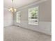 Carpeted living room with elegant chandelier, wainscoting, and sunlit windows, perfect for relaxing at 2345 Gallard St, Lawrenceville, GA 30043