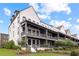 View of townhomes with covered front porches and landscaped lawns against a blue sky with clouds at 6710 Pippin Walk, Alpharetta, GA 30005