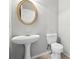 Clean, updated bathroom with a modern pedestal sink, a round mirror, and a toilet at 5487 Walnut Lane Ln, Stonecrest, GA 30038