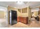 Basement area featuring a corner kitchenette with wooden cabinets, a black refrigerator, and tile flooring at 5600 Buck Hollow Dr, Alpharetta, GA 30005