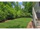 Large backyard featuring a well-maintained lawn, mature trees, and wood stairs at 328 Shade Tree Cir, Woodstock, GA 30188