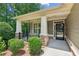 Inviting front porch features stone supports, white columns, black railing and a glass front door at 328 Shade Tree Cir, Woodstock, GA 30188