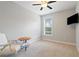 Bright bedroom features a ceiling fan, chair and table and mounted TV near the window at 4814 Little Cove Ct, Auburn, GA 30011