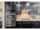 Modern kitchen featuring dark cabinets, stainless steel appliances, and granite countertops at 4814 Little Cove Ct, Auburn, GA 30011