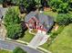 Aerial view of a brick home with a 2-car garage, manicured lawn, and mature trees at 5054 Kingsbridge Pass, Powder Springs, GA 30127