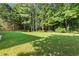 Large, grassy backyard enclosed by a wooden fence and surrounded by trees at 5054 Kingsbridge Pass, Powder Springs, GA 30127