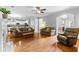 Open-concept living room featuring hardwood floors, a ceiling fan, and comfortable seating at 5054 Kingsbridge Pass, Powder Springs, GA 30127