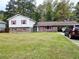 Split-level home featuring a large front yard, brick accents, red shutters, and a convenient carport at 7437 Grayson Dr, Riverdale, GA 30296