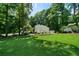Spacious backyard featuring a wooden deck, lush landscaping, mature trees, and a shed for outdoor storage at 86 Kelly Ct, Dallas, GA 30157