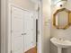Well-lit half bathroom with pedestal sink, decorative mirror, and storage closet nearby at 1413 Eastbrooke Way, Marietta, GA 30066