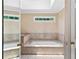 Relaxing bathtub in a tiled bathroom with a skylight allowing natural light to enter the space at 4211 Schooner Ne Ct, Roswell, GA 30075
