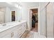 Bright Primary bathroom featuring double sinks, white cabinetry, and a doorway that leads to a spacious walk-in closet at 515 Cobblestone Ct, Canton, GA 30115