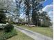 Landscaped front yard with long driveway to brick home amongst mature trees on sunny day at 1534 Cooper Lake Se Rd, Smyrna, GA 30082