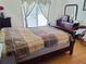 A cozy bedroom features hardwood floors, a comfortable bed, a bedside table, and natural light through window at 2905 Olde Town Park Dr, Norcross, GA 30071