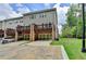 Townhome featuring a rear view with multi-car parking, back patios, garage doors, and a manicured lawn at 711 Topsail Ln, Alpharetta, GA 30005