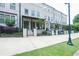 Elegant townhouse exteriors featuring painted brick, covered porches, iron fences, and sidewalk at 5836 Sandy Springs Cir, Atlanta, GA 30328