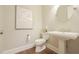 Elegant powder room with a pedestal sink, toilet, and decorative mirror at 5836 Sandy Springs Cir, Atlanta, GA 30328