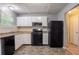 Traditional kitchen with white cabinetry, black appliances, and neutral countertops at 1377 Mill Lake Cir, Stone Mountain, GA 30088