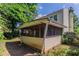 Enclosed screened in porch attached to a two-story home with a view of the overgrown lawn at 1377 Mill Lake Cir, Stone Mountain, GA 30088