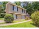 View of a two-story home featuring beige siding, black shutters, and a sidewalk in a lush green yard with trees at 2957 Temple Johnson Rd, Snellville, GA 30039