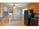 A kitchen featuring wooden cabinets, black appliances, and neutral tile flooring, adjoining stairs to the upper levels at 130 Mimosa Dr, Fayetteville, GA 30214