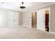 Spacious bedroom features neutral carpet, a ceiling fan, and double doors to closet and ensuite at 35 Inverleigh Row, Covington, GA 30014