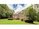 Back exterior showcasing a brick home, covered porch, groomed lawn, and mature trees at 35 Inverleigh Row, Covington, GA 30014