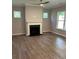 Cozy living room with a fireplace, large windows providing natural light, hardwood floors, and modern ceiling fan at 3032 Farm Tract Trl, Woodstock, GA 30189