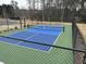 Community pickleball court with a green and blue surface, surrounded by a black chain-link fence, offering recreational fun at 3032 Farm Tract Trl, Woodstock, GA 30189