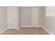 A bedroom with neutral walls, carpet flooring, and two white doors at 6914 N Baggett Rd, Douglasville, GA 30134