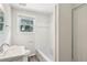 Bathroom featuring a single sink vanity, bathtub with white tile surround, and wire rack shelving at 6160 King Arthur Dr, Douglasville, GA 30135