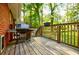 A wooden back deck features a grill, railing, and serene views of the surrounding trees at 2343 Hunting Valley Dr, Decatur, GA 30033
